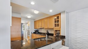 Cocina moderna con armarios de madera, encimera de granito, pileta de acero inoxidable y un taburete de bar.