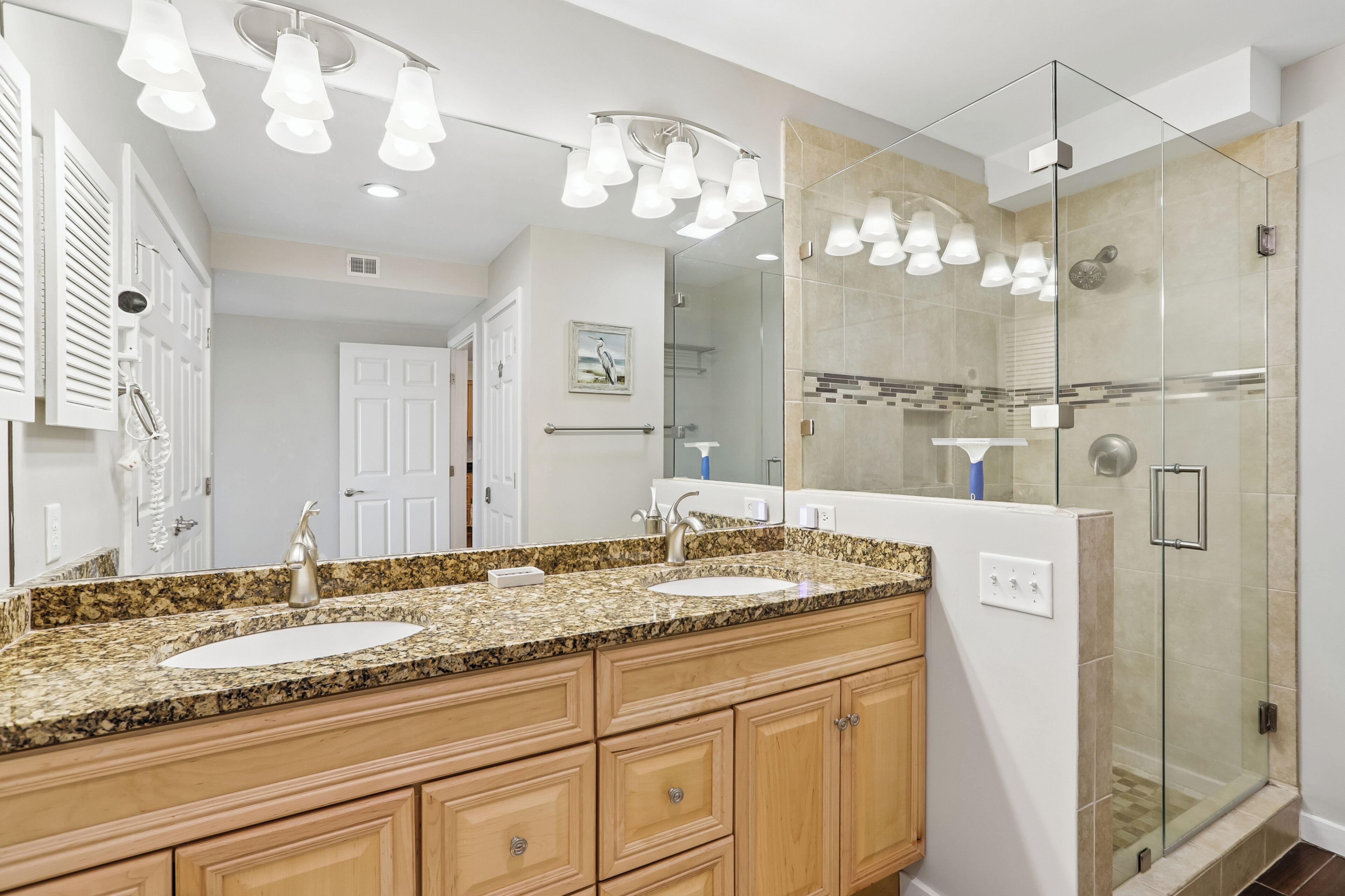 A bathroom with a double sink vanity, a glass shower enclosure, and a large mirror.