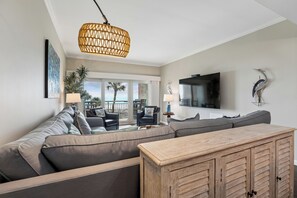 A modern living room with a sectional sofa, a wooden cabinet, and a large TV.
