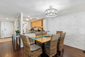 A modern kitchen with wooden cabinets, a dining table with wicker chairs, and a unique textured wall.