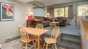 A living room with a dining table, two sofas, a coffee table, and a fireplace. - Ski-In/Ski-Out Sunday River Condo: Sunrise A-104 (Newry)