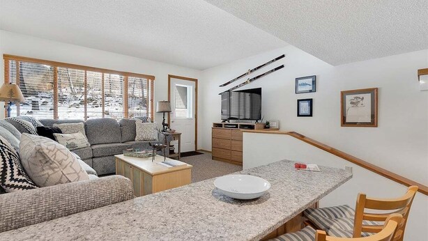 Una sala moderna con un sofá, una mesa de comedor y una zona de cocina.