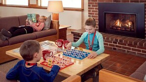Una sala de estar acogedora con chimenea, una mesa de centro con juegos de mesa y un sofá.