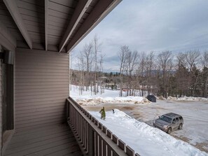 A covered porch with a view of a snowy landscape and a parked vehicle.