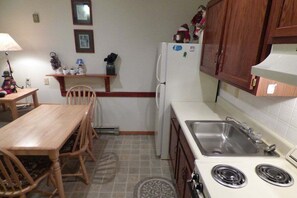 A compact kitchen with a dining table, chairs, a refrigerator, a stove, and a sink. - Ski-In/Ski-Out Sunday River Condo: Sunrise C-102 (Newry)