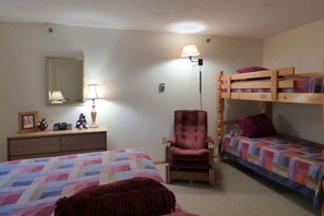 Ein Schlafzimmer mit zwei Etagenbetten, einem Sessel, einem Schminktisch und einer Lampe.