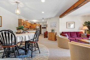 Amplia sala de estar con mesa de comedor, sillas, sofá y cocina al fondo.
