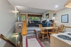 A compact living space with a dining area, sofa, and a staircase leading to an upper level.