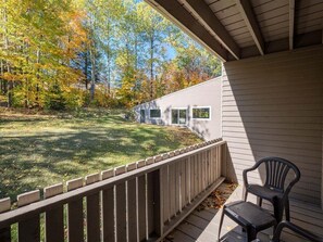 A covered porch with a view of a grassy yard and trees.