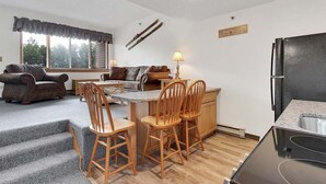 A compact living space with a dining area, kitchen, and seating area. - Ski-In/Ski-Out Sunday River Condo: Sunrise A-133 (Newry)
