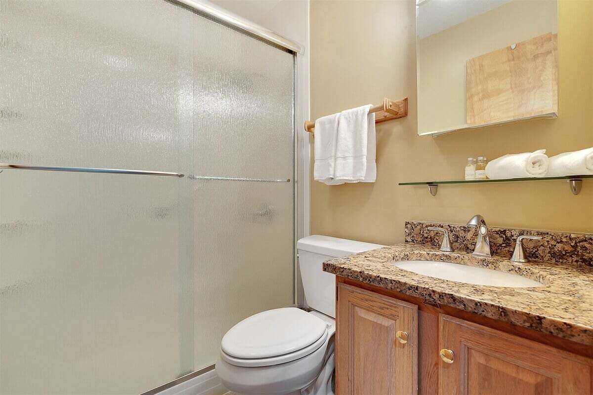 Un baño con ducha, inodoro, lavabo y espejo.
