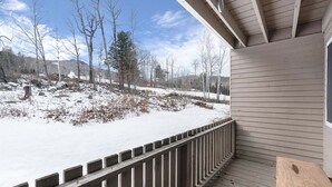 Un rivestimento in legno con ringhiera, vista su un paesaggio innevato e un edificio con tetto a capanna.