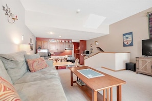 Un espacio habitable compacto con sofá, mesa de comedor, zona de cocina y televisión.