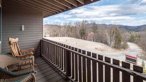 A covered porch with a view of a mountainous landscape.