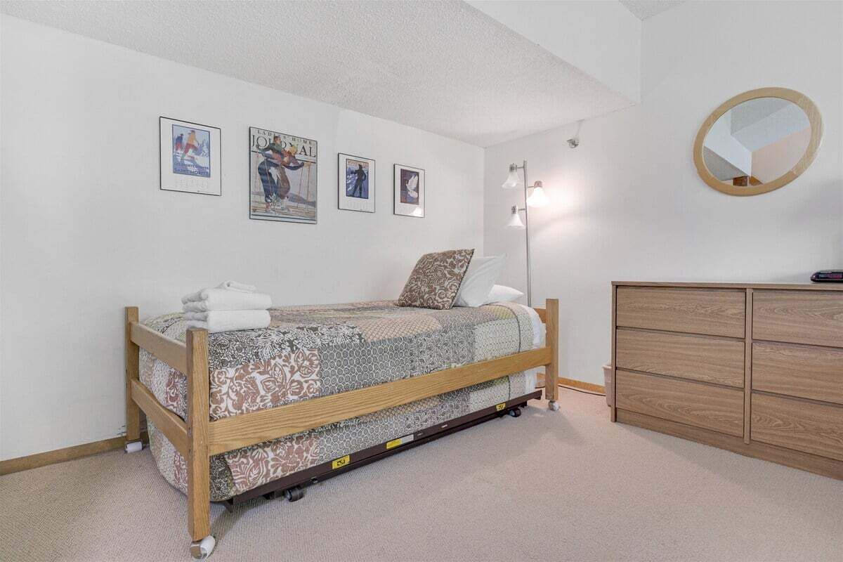 A bedroom with a bed, a dresser, a mirror, and wall art.