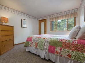 A bedroom with a bed, dresser, window, and door. - Brookside 1 B-104 - Sunday River Slopeside Condominium (Newry)