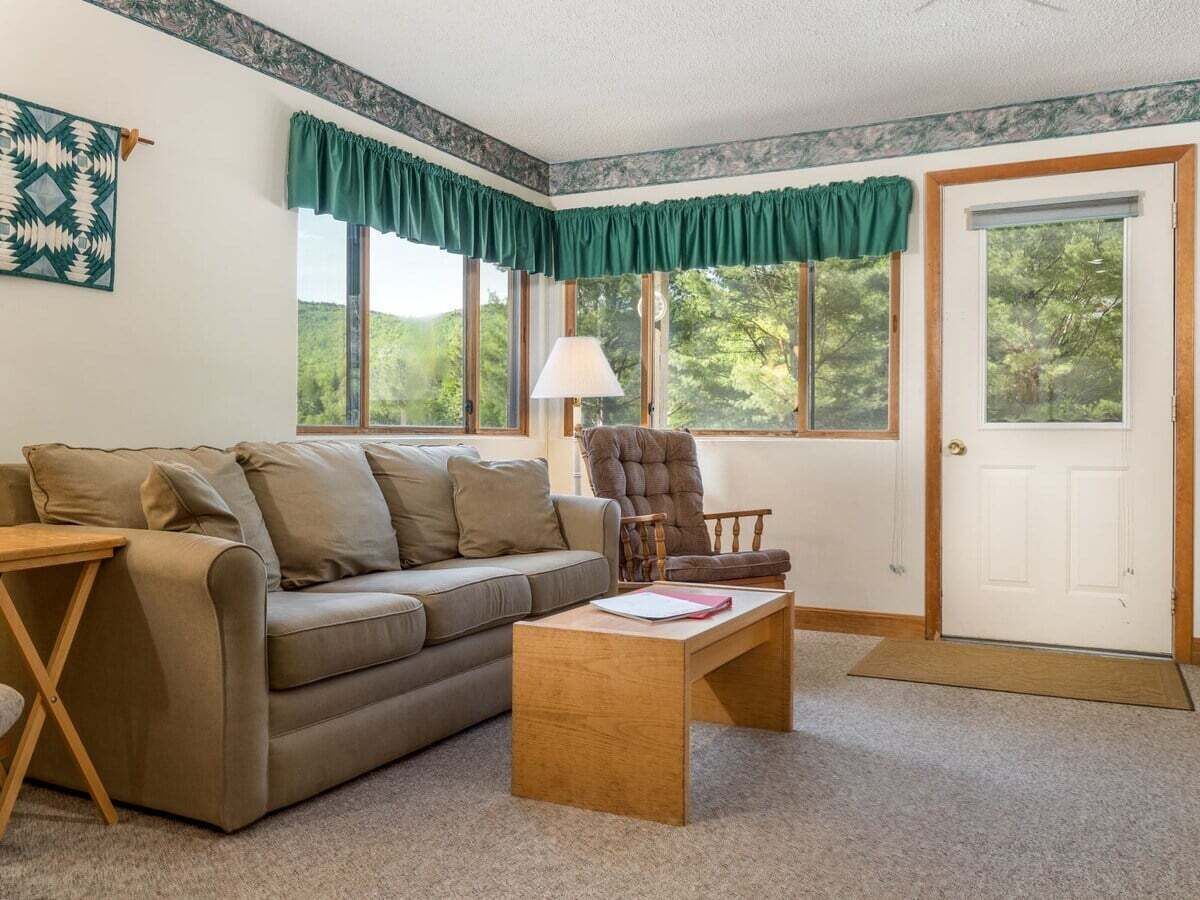 A living room with a sofa, armchair, coffee table, and a door with windows.