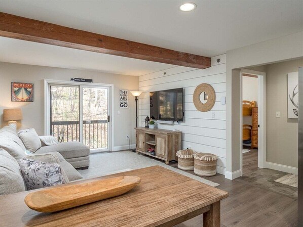 A living room with a sofa, a wooden table, a TV, and a fireplace.