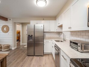 Una cocina moderna con armarios blancos, electrodomésticos de acero inoxidable y encimera de mármol.