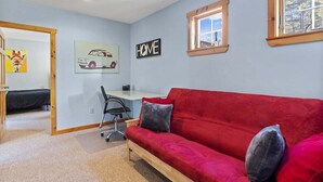 A room with a red sofa, a desk, a chair, and a 'HOME' sign on the wall.