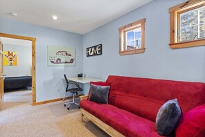 A room with a red sofa, a desk, a chair, and a 'HOME' sign on the wall.