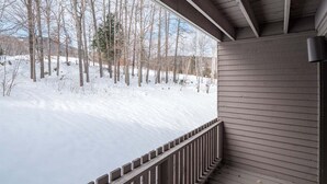 A covered porch with a view of a snowy landscape and trees. - Ski-In/Ski-Out Sunday River Condo: Sunrise A-120 (Newry)