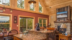 A spacious kitchen with granite countertops, a fireplace, and large windows.