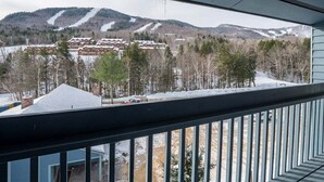 Blick vom Balkon mit Geländer auf eine verschneite Landschaft mit Gebäuden und Bäumen.