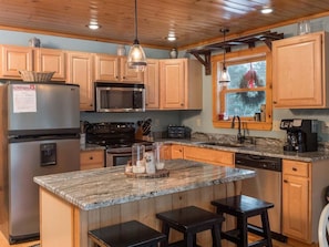 A kitchen with wooden cabinets, a granite countertop, a stainless steel refrigerator, a microwave, a stove, and a coffee maker. - Countryside Retreat - Mountain Style Chalet (Bethel)