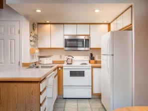 A compact kitchen with a microwave, stove, and refrigerator. - Riverbend 41: Two bedroom Condo (Bethel)