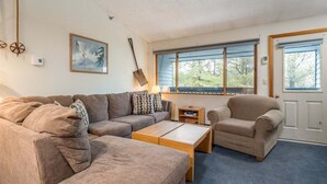 Una sala de estar con un sofá, sillón, mesa de centro y un cuadro en la pared.