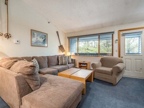 Una sala de estar con un sofá, sillón, mesa de centro y un cuadro en la pared.
