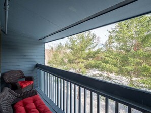 Un balcón con vistas a árboles y una terraza de madera.