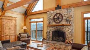 A cozy living room with a stone fireplace, leather sofas, and a wooden ceiling. - Powder Ridge Mountain Retreat (Newry)
