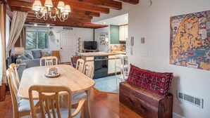 Un ambiente acogedor con una mesa de comedor de madera, sillas, un sofá, una zona de cocina y un mapa en la pared.