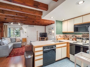 Cocina compacta con lavavajillas, estufa y comedor con mesa y sillas.