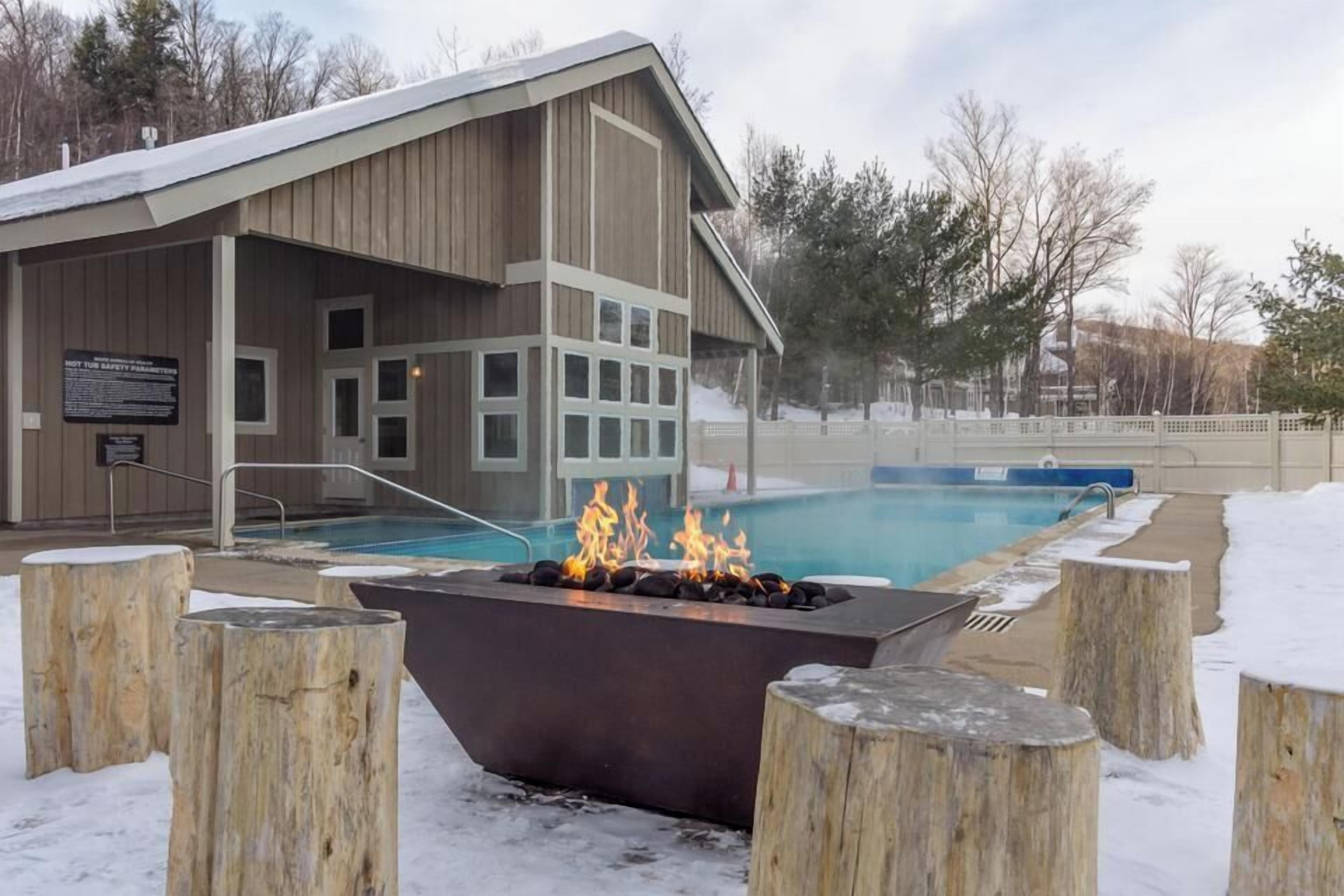 Ein Gebäude mit Pool, Feuerstelle und verschneiter Außenanlage.