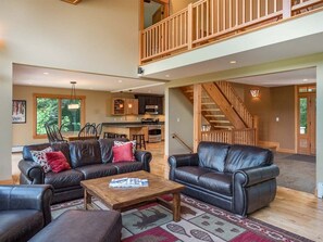 A spacious living area with leather sofas, a wooden coffee table, and a staircase leading to an upper level. - Peaks Hideaway at Sunday River (Newry)
