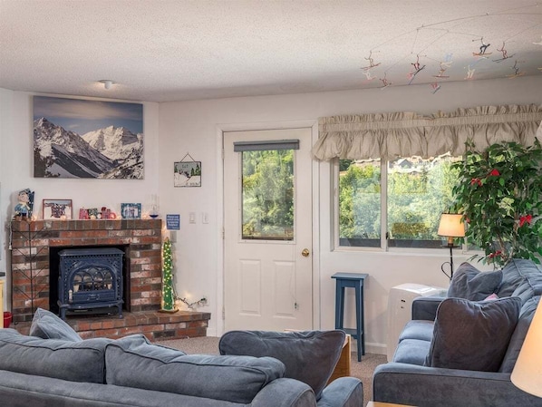 A living room with a fireplace, a couch, a plant, and a window with curtains.