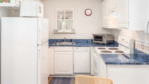 A compact kitchen with white appliances, a blue countertop, a microwave, a toaster, and a sink. - Sunday River Condo: Brookside I B-306 (Newry)