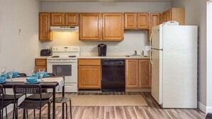 Una cocina funcional con armarios de madera, una estufa blanca, lavavajillas y refrigerador.