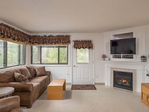 Una sala de estar con chimenea, televisor y sofá.