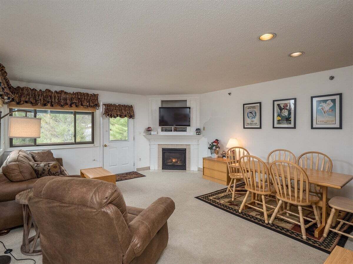A living room with a fireplace, a television, a dining table with chairs, and a sofa.