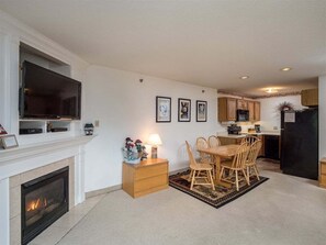 Una sala de estar con chimenea, televisor y comedor con sillas de madera y una mesa.