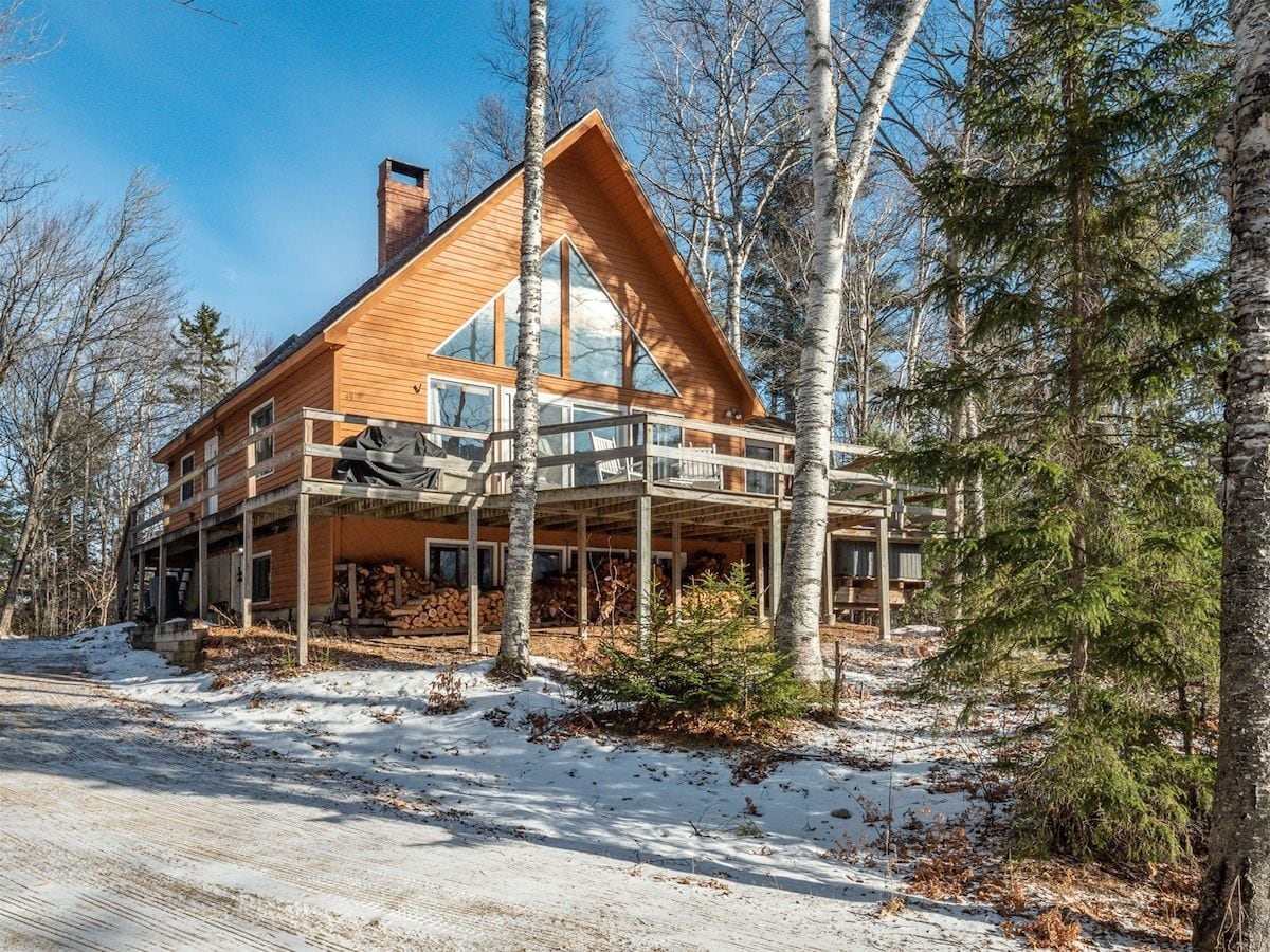 Een chalet met houten gevel, grote ramen en een overdekt terras.