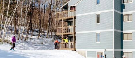 Un immeuble à plusieurs étages doté de balcons, d’une piste de ski et d’un télésiège.