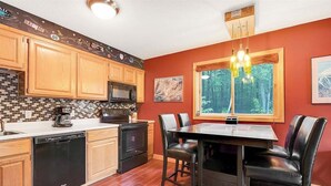 A kitchen with wooden cabinets, a microwave, and a dining table with chairs. - White Cap A-104 - Sunday River Condo (Newry)