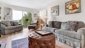 Un salon avec deux canapés, une table basse et un escalier menant à un balcon.