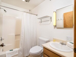 A bathroom with a shower, toilet, sink, and a mirror.