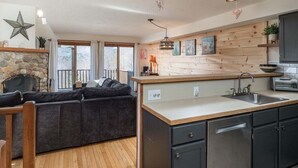 Una cocina moderna con chimenea de piedra, detalles de madera y una isla integrada con lavamanos.